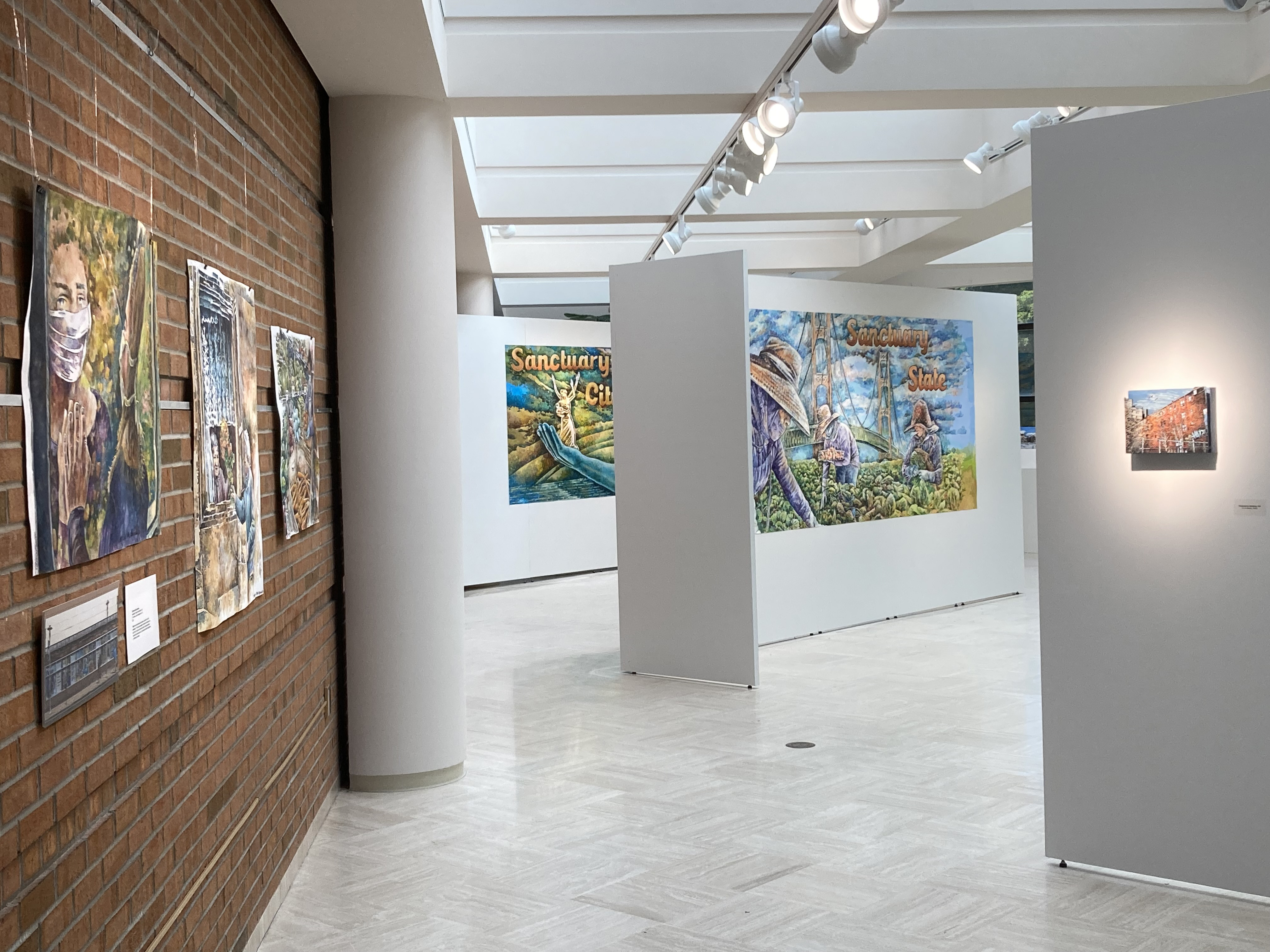installation looking south toward outer windows - watercolors along brick wall, portions of billboards, small relief painting (l-r)